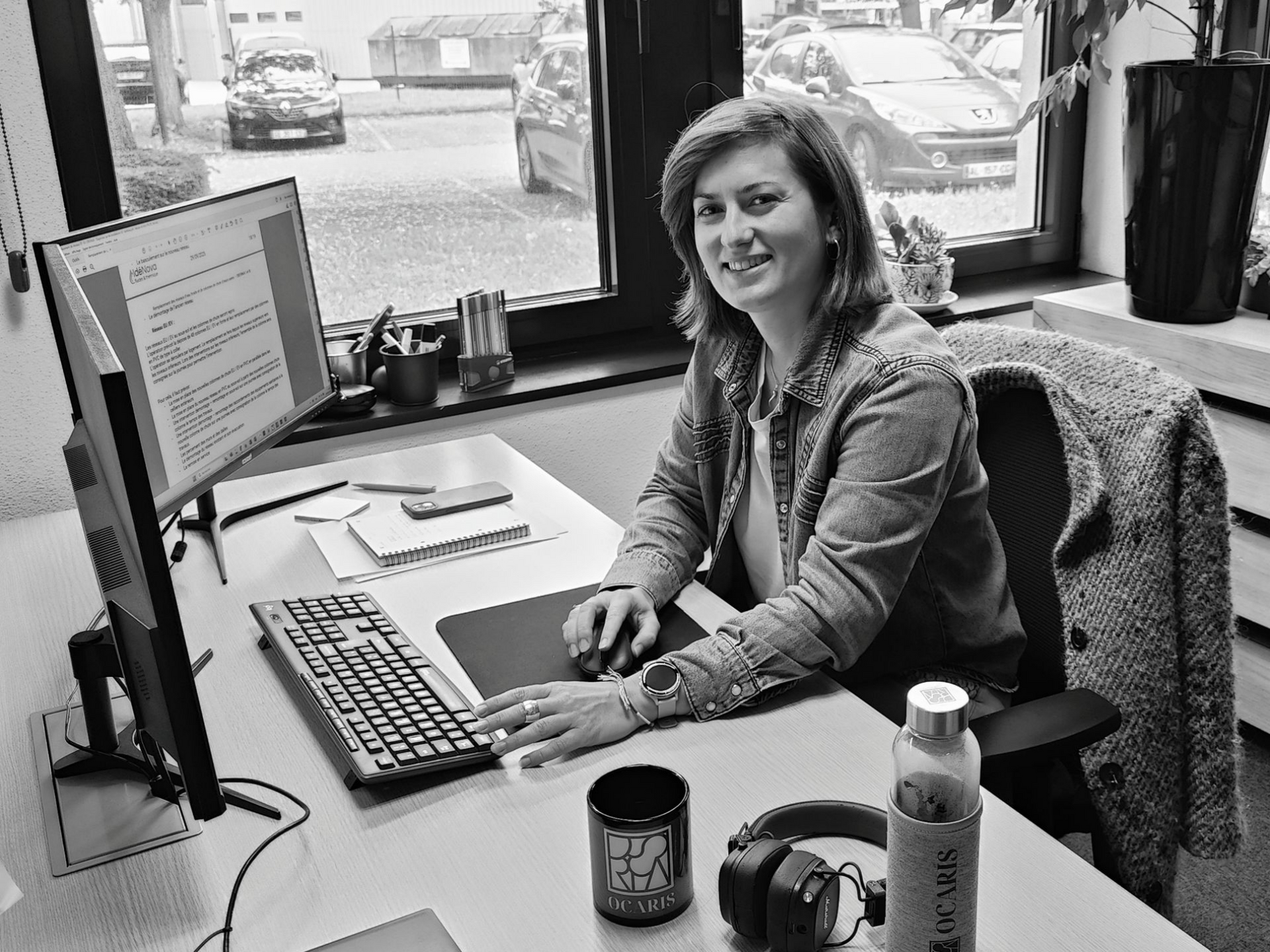 Sophia Auelin sourit en travaillant à un bureau avec un ordinateur.