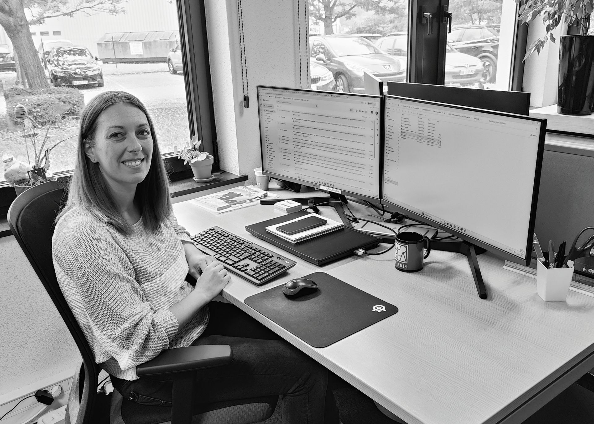 Sophie Rudolf souriante à un bureau avec deux écrans.