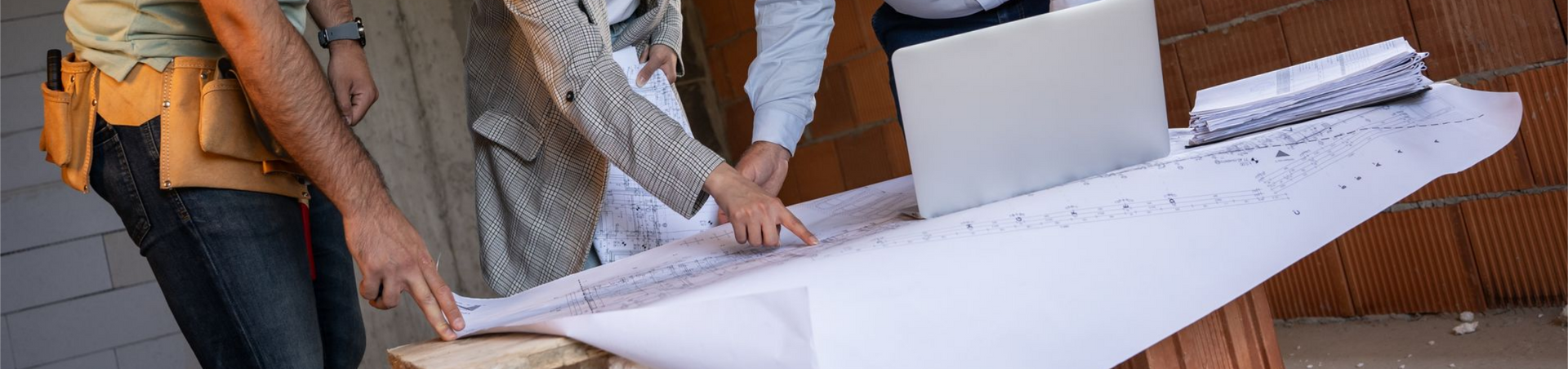 Des personnes regardent une grande feuille blanche. Elles sont debout autour d'une table.
