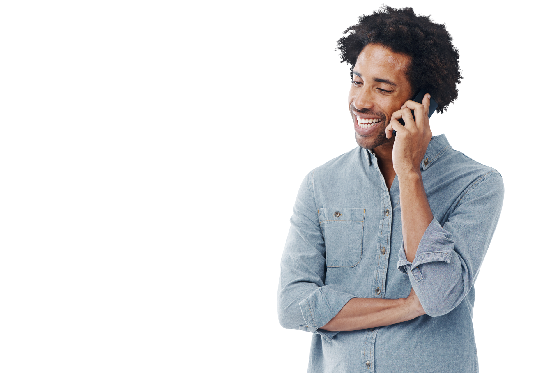 Un homme aux cheveux bouclés sourit tout en parlant au téléphone, les bras croisés.