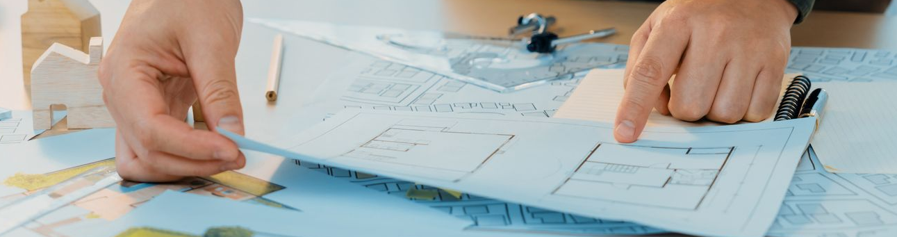 Mains pointant vers un plan d'étage sur une table, peut-être un plan.