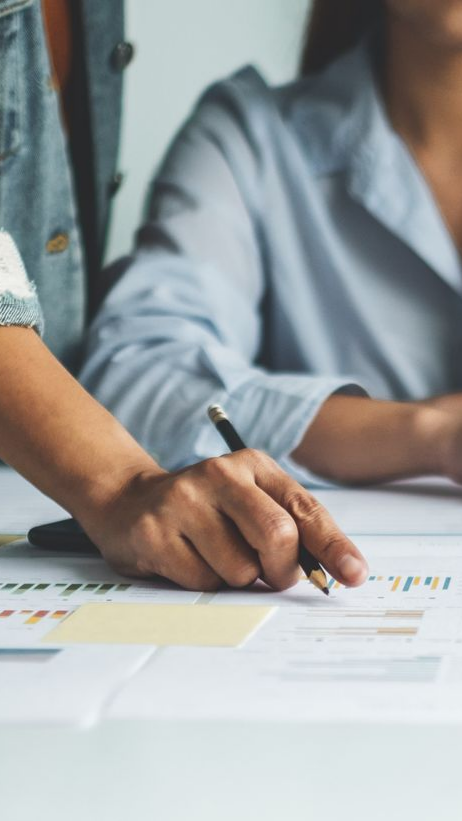 Mains de deux personnes pointant des documents financiers.