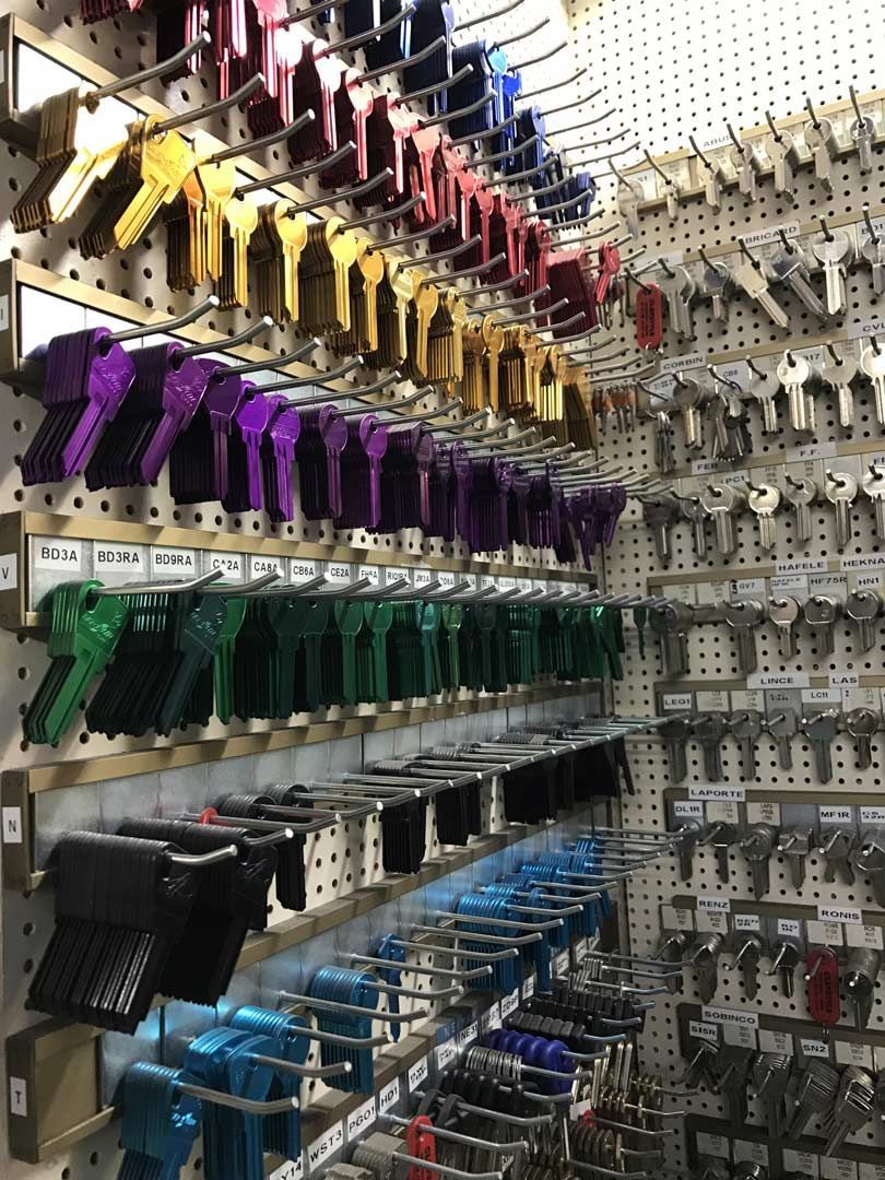Râtelier industriel à code couleur, avec des rangées de serre-joints et de poignées suspendus dans un atelier.