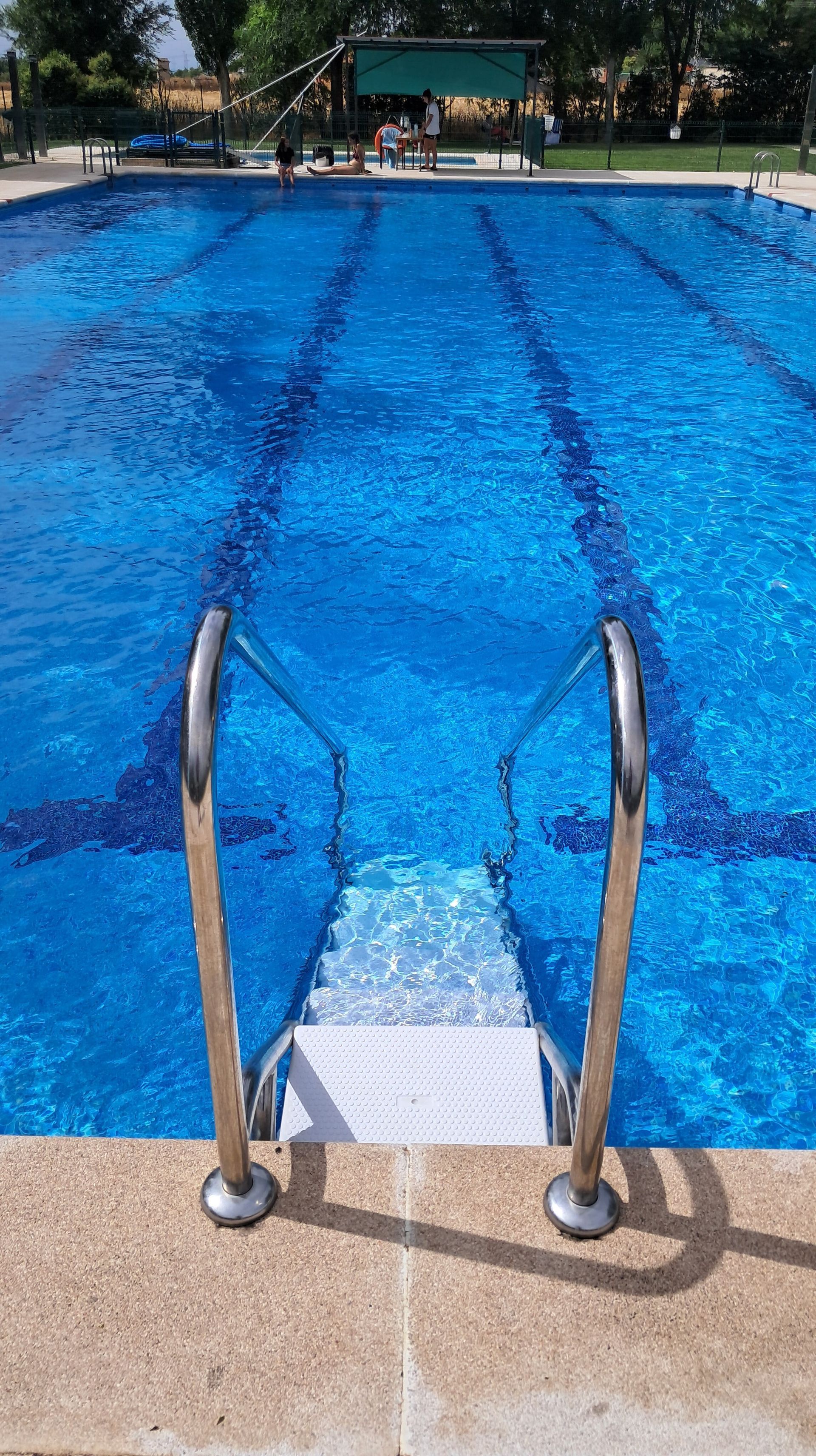 Piscina azul con escalones de acero inoxidable.