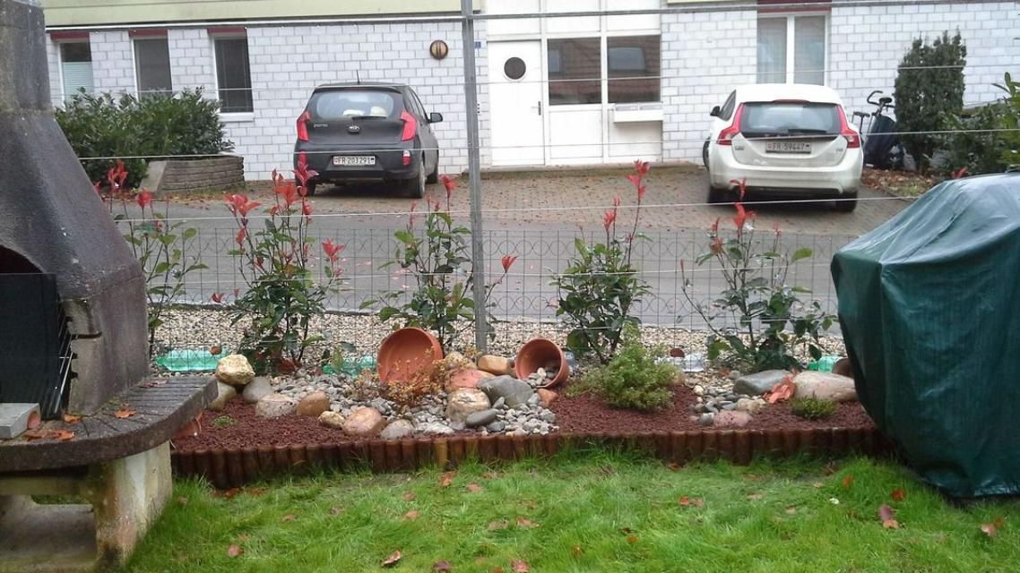 Deux voitures sont garées devant une maison en briques blanches.