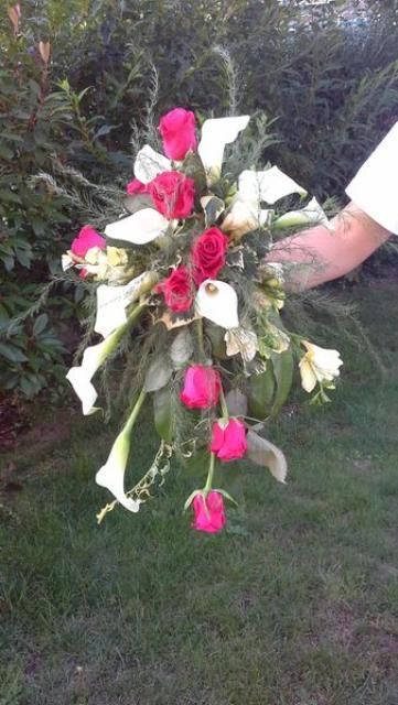 Une personne tient un bouquet de fleurs rouges et blanches.