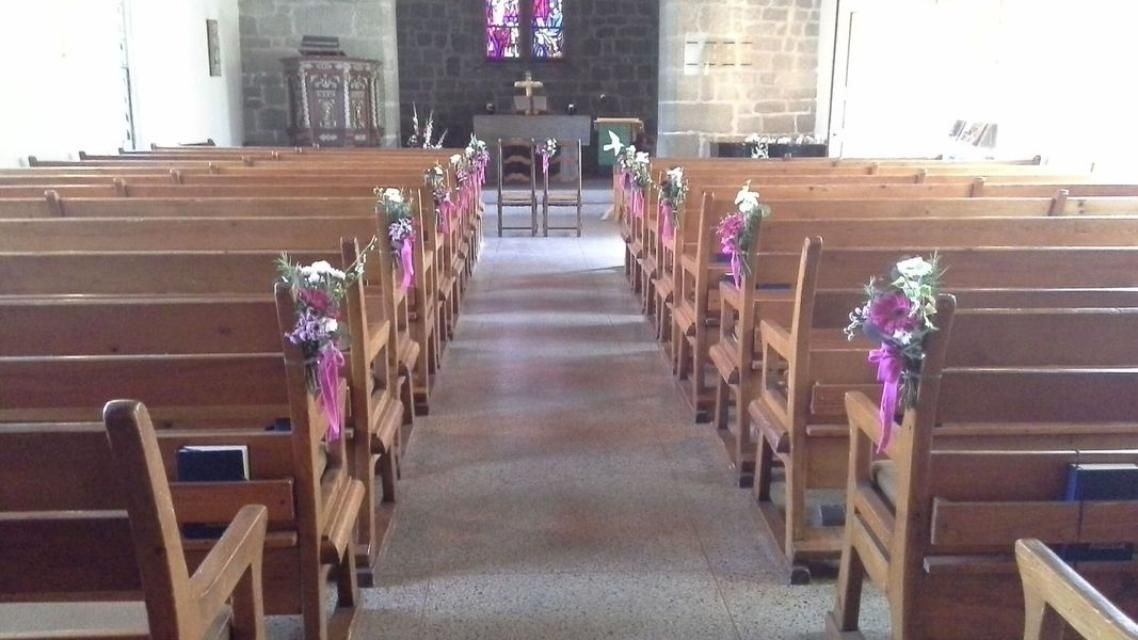 Rangées de bancs en bois dans une église décorée de fleurs