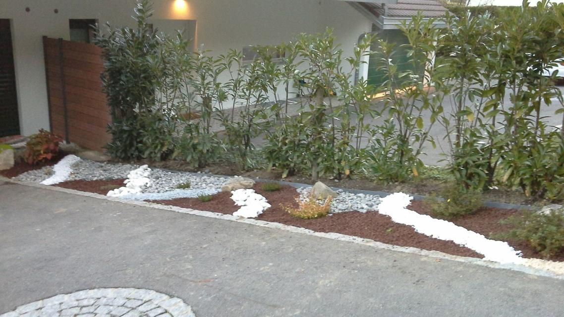 Une rangée de rochers et de plantes devant une maison.