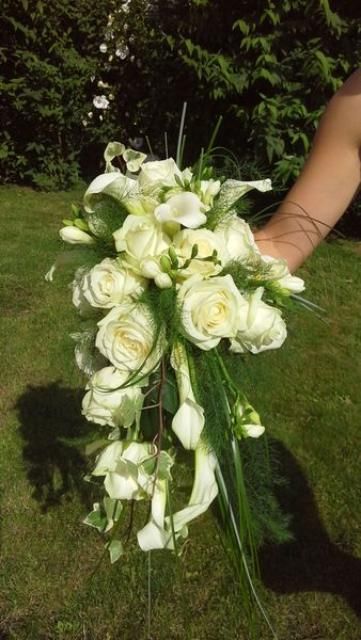Une personne tient un bouquet de fleurs blanches dans sa main.