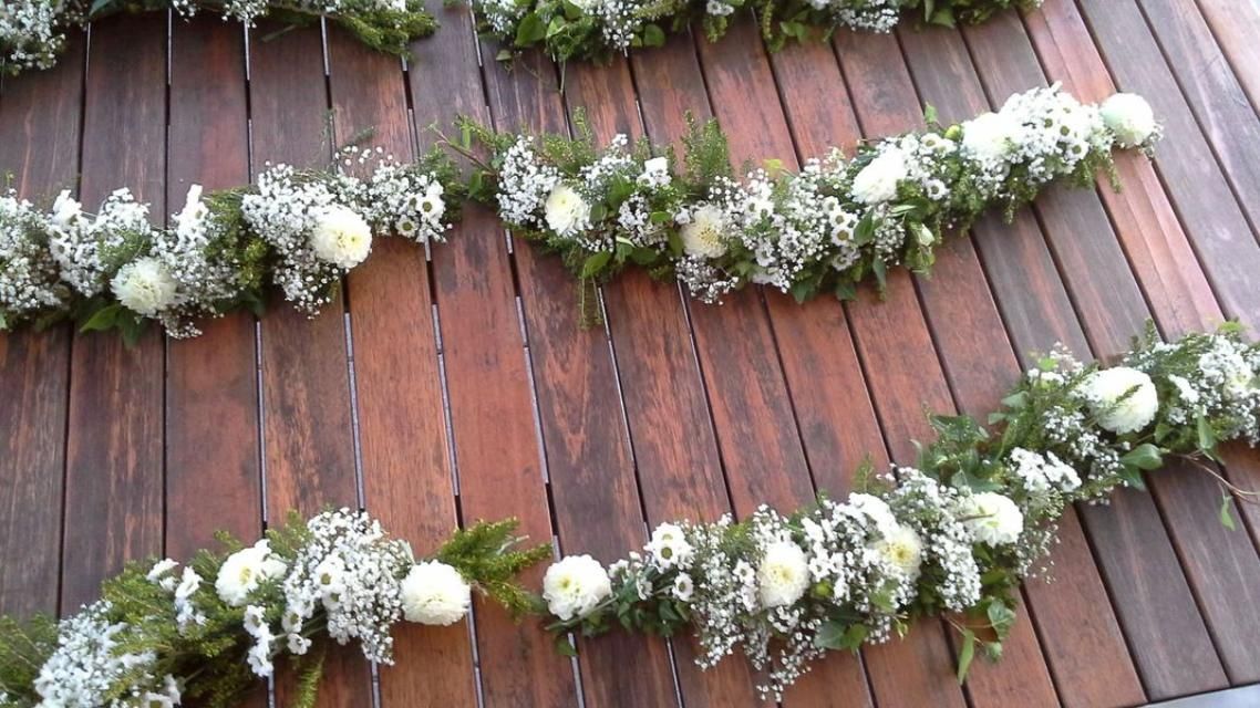 Un bouquet de fleurs blanches est accroché à un mur en bois