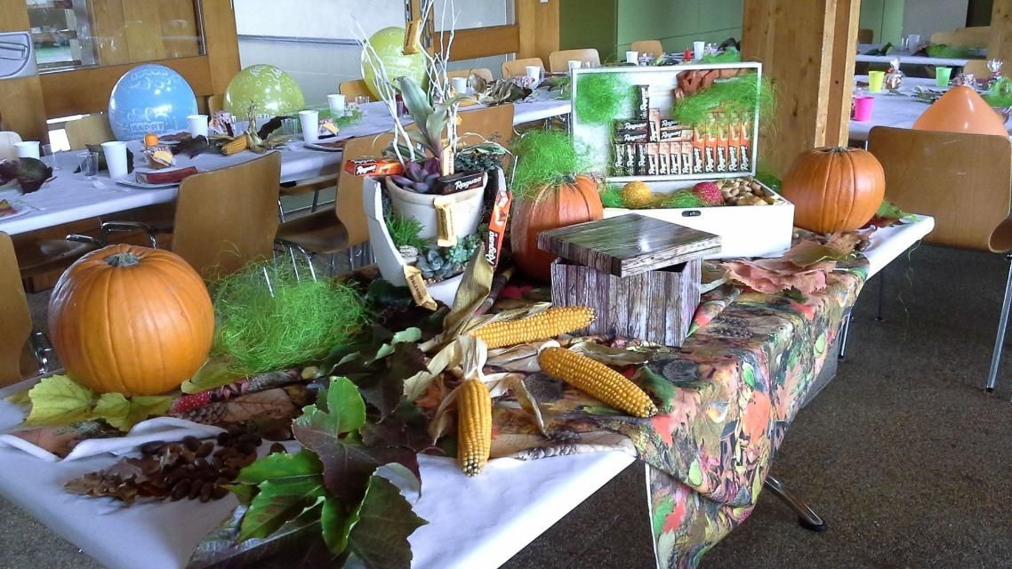 Une table avec des citrouilles et des feuilles dessus