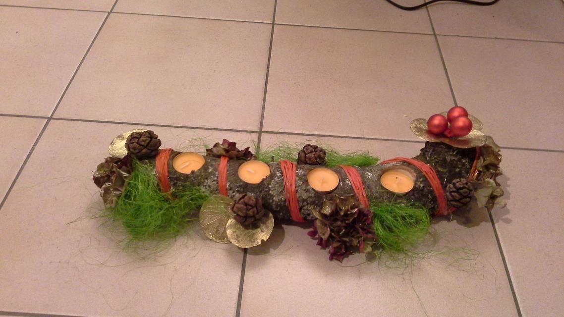 Une bûche avec des bougies dessus est posée sur un sol carrelé.