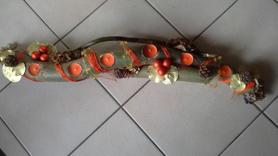 Un long morceau de bois avec des fleurs et des bougies dessus est posé sur un sol carrelé.