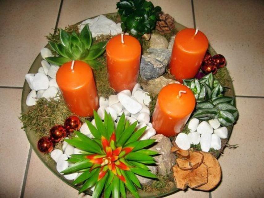 Quatre bougies oranges sont entourées de plantes et de rochers