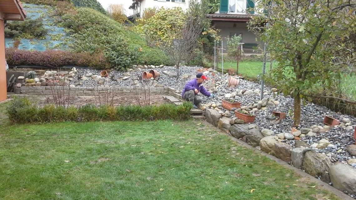 Un homme travaille sur un mur de pierre dans un jardin.