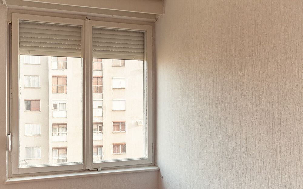 Una habitación vacía con una ventana y un edificio al fondo.