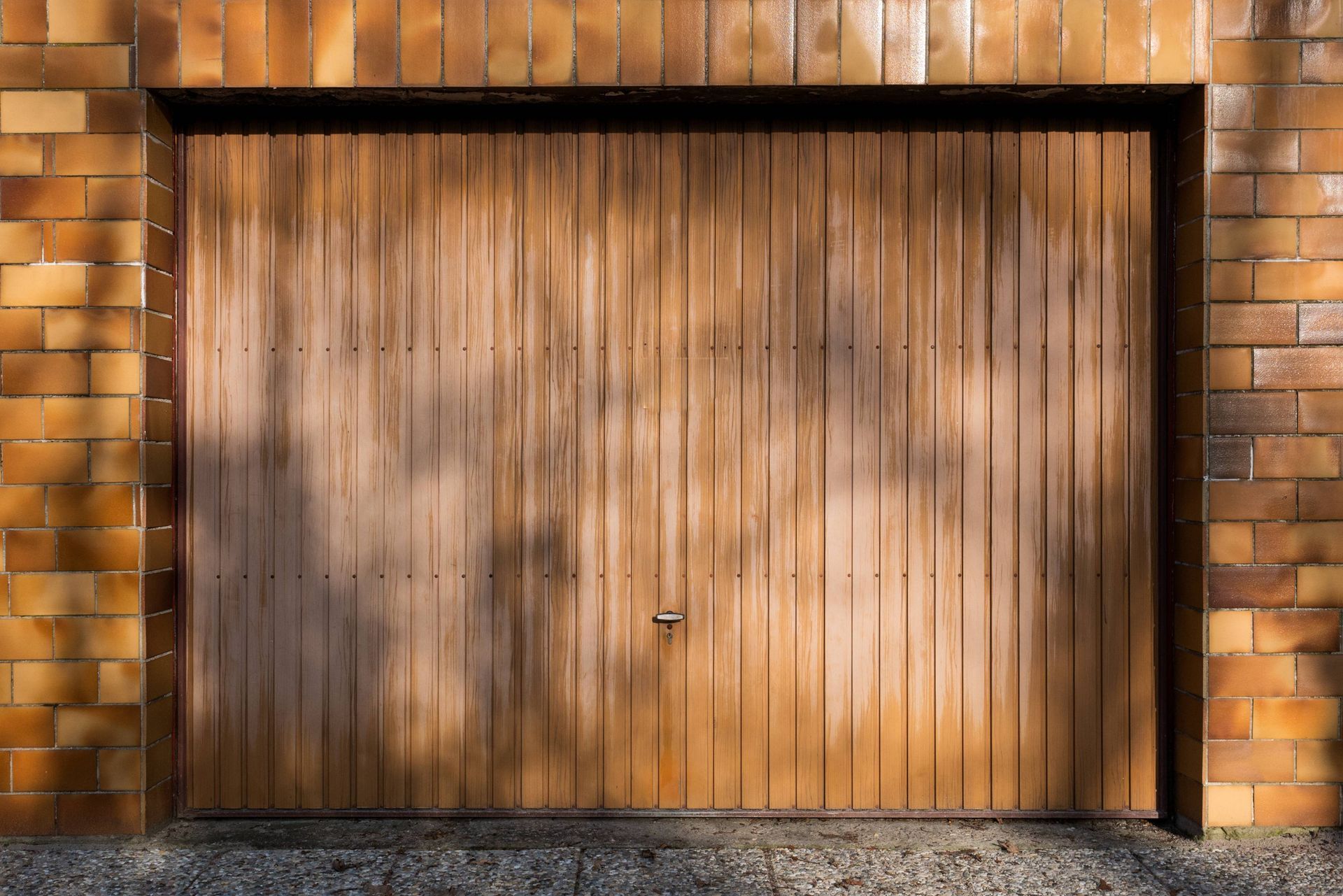 Una puerta de garaje de madera está contra una pared de ladrillos.