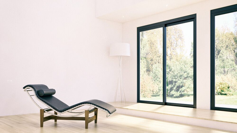 Un sillón está sentado en una sala de estar al lado de una ventana.