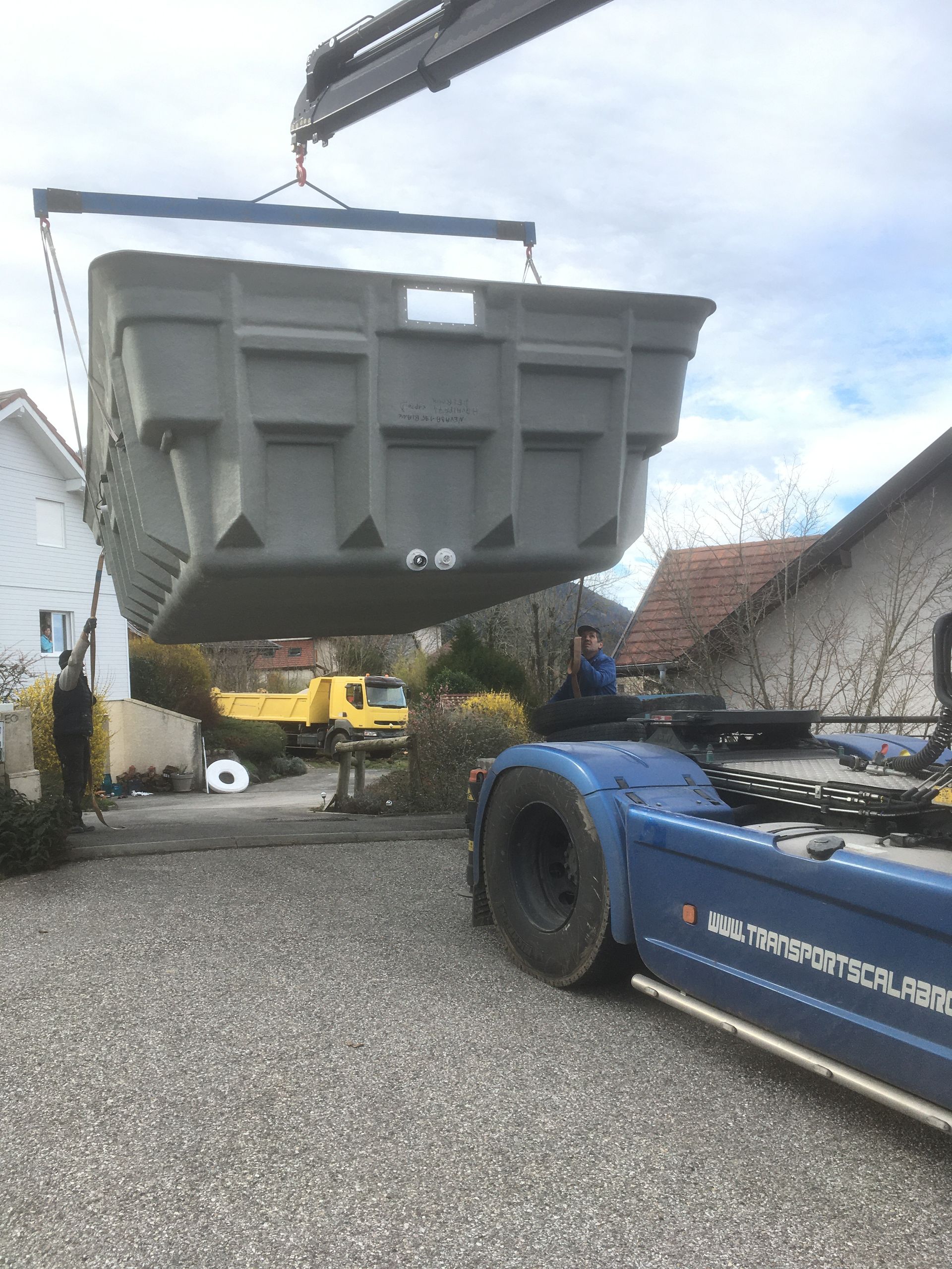 Photo du grutage d'une piscine coque dans le jardin d'un client