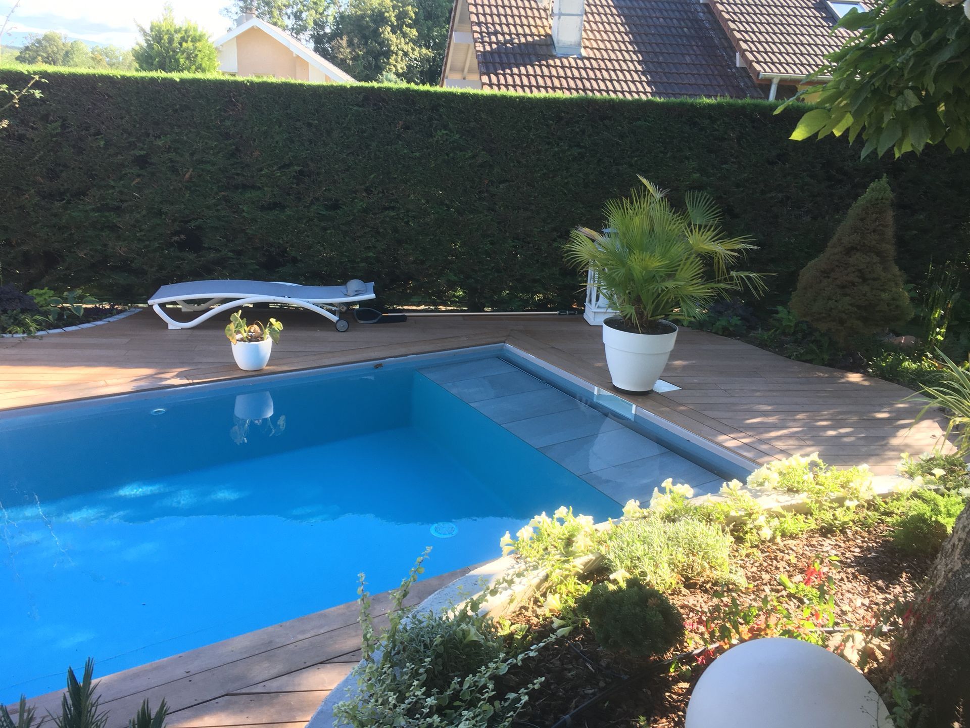 Photo d'une piscine enterrée, d'une terrasse en bois et d'un jardin