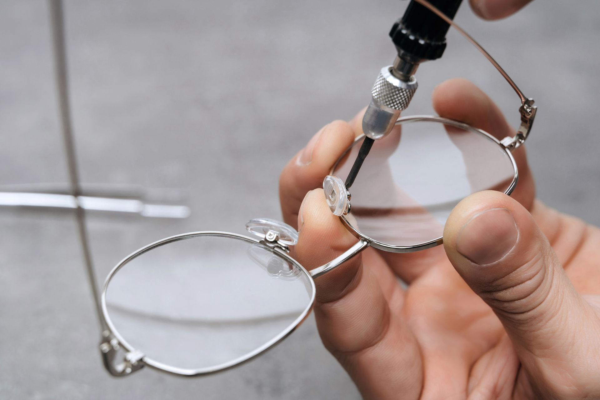 Gros plan sur la réparation de plaquette nasale de lunettes dans un atelier.