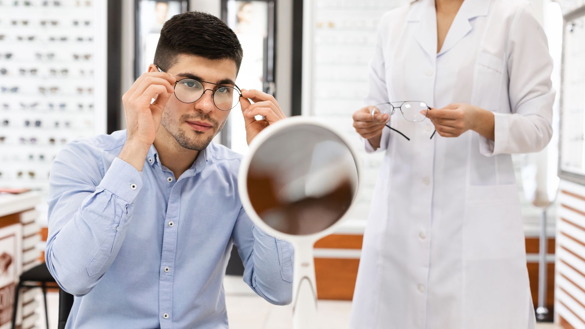 Un professionnel aide un homme à choisir des lunettes de vue dans un magasin d'optique.