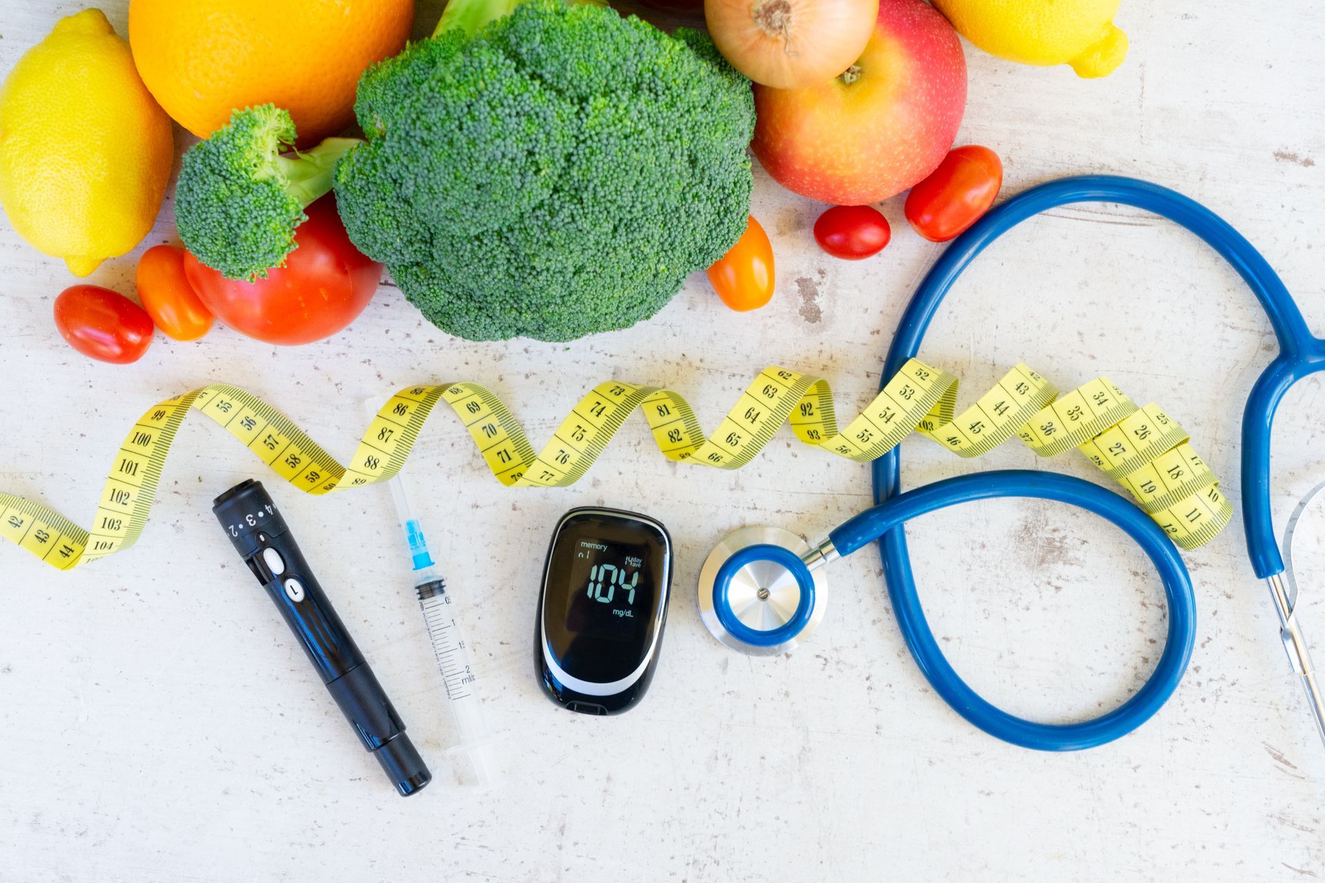 Des légumes à côté d'un stétoscope et d'un lecteur de glycémie