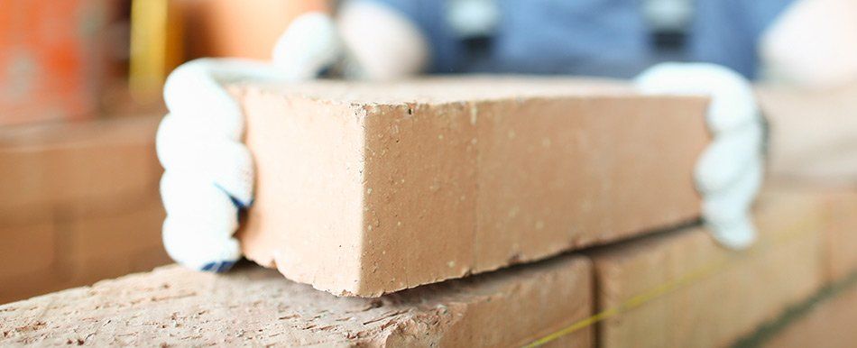 Un maçon pose une brique sur un mur en construction