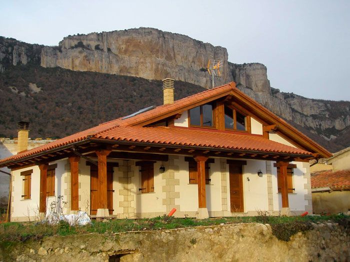 Una casa con una montaña al fondo tiene un techo de tejas rojas.