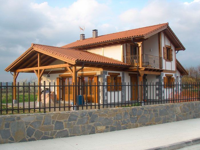 Una casa con techo de tejas rojas y pared de piedra