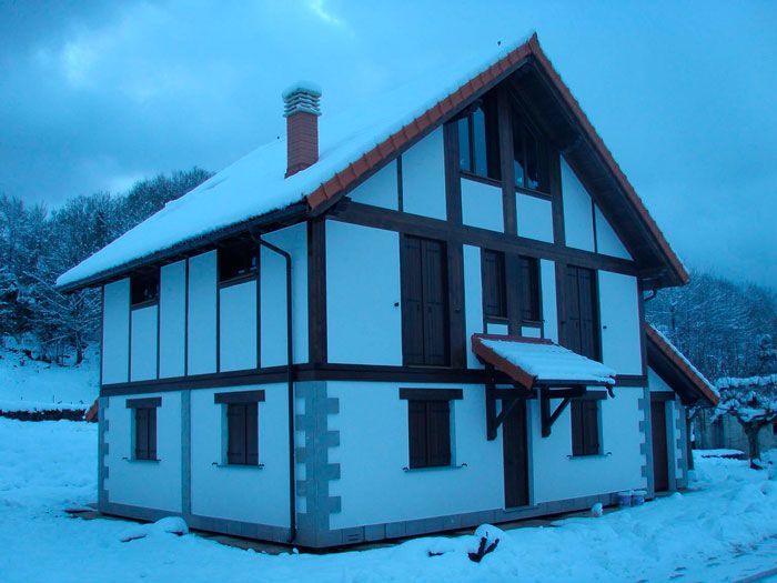 Una casa blanca y marrón está cubierta de nieve.