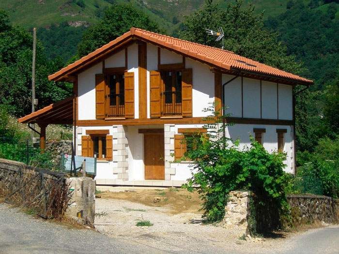 Una casa blanca y marrón con techo rojo