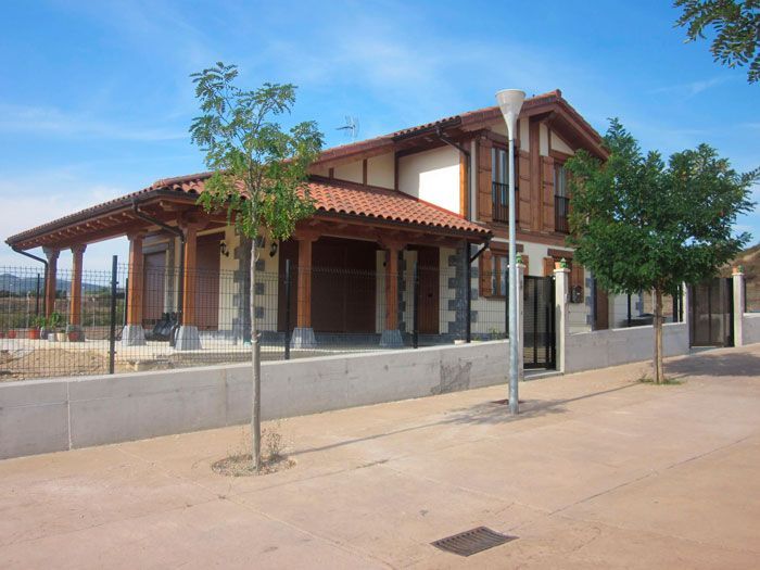 Una casa grande con techo de tejas rojas y una valla alrededor.
