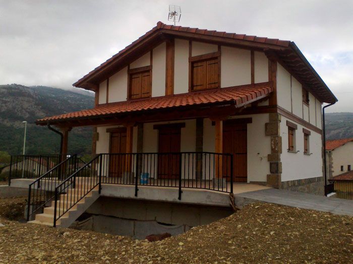 Una casa blanca con techo de tejas rojas y un balcón
