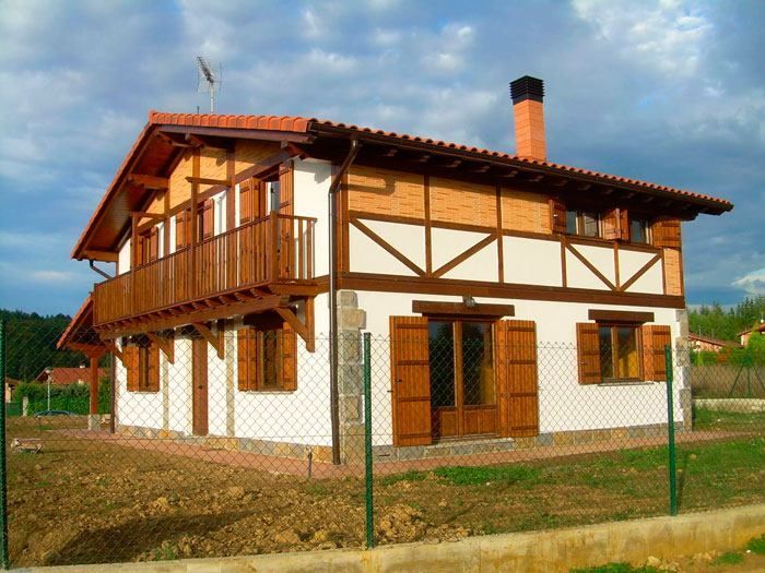 Una casa blanca con techo de tejas rojas y molduras de madera