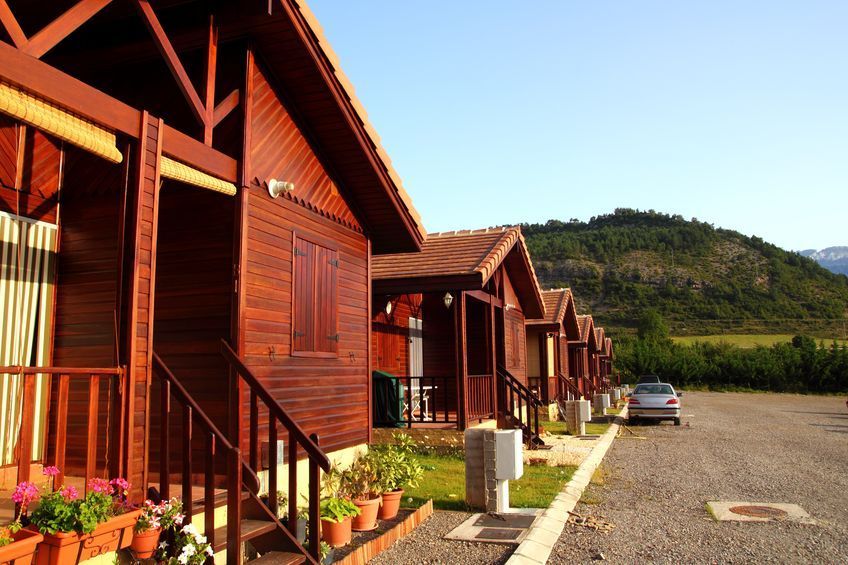 Una hilera de cabañas de madera con un coche aparcado delante de ellas.