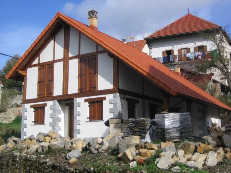 Una casa blanca y marrón con techo rojo