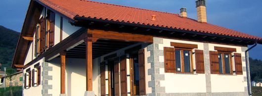 Una casa blanca con techo de tejas rojas y contraventanas de madera