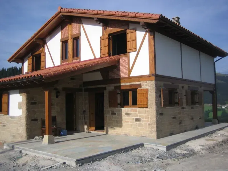 Una casa blanca y marrón con techo de tejas rojas