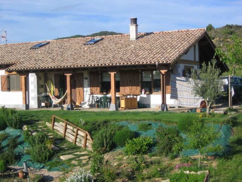 Una casa con techo de ladrillo y una hamaca delante