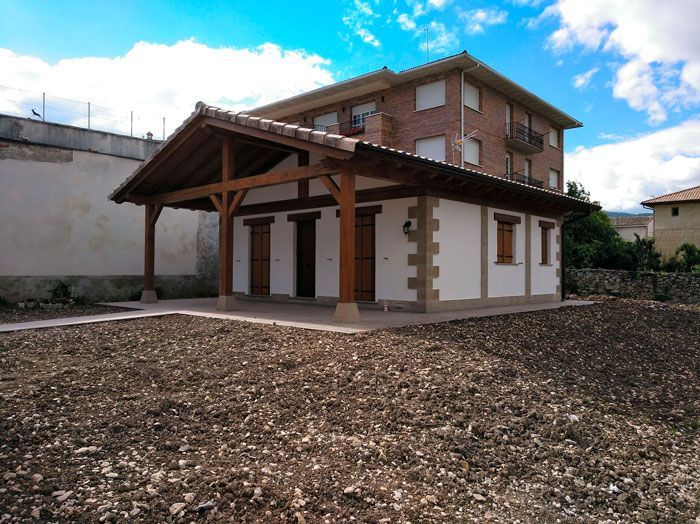 Un pequeño edificio con techo de madera se encuentra en medio de un campo de tierra.
