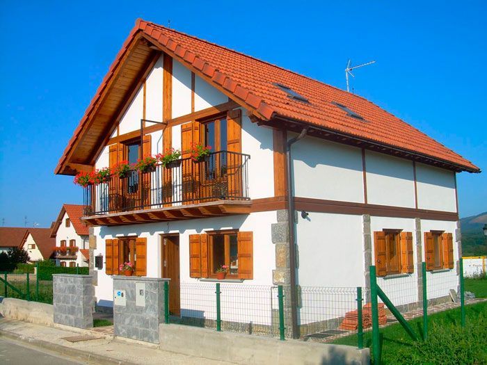 Una casa blanca con techo rojo y contraventanas de madera
