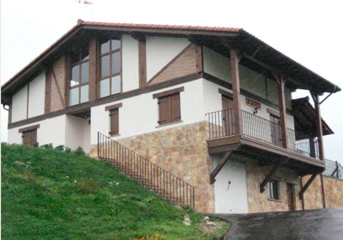 Una casa blanca y marrón con balcón y escaleras.