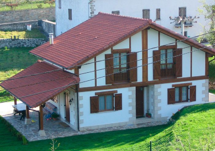 Una casa blanca con techo rojo y molduras de madera