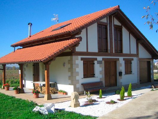 Una casa blanca y marrón con techo de tejas rojas