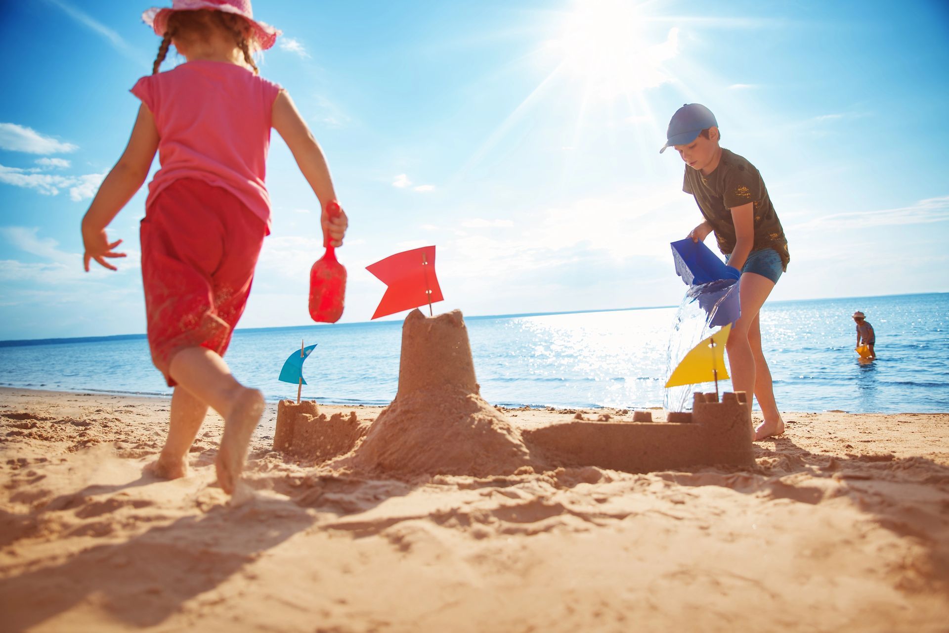 Two children are playing in the sand on the beach.