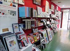 Una tienda llena de libros y cuadros en los estantes.