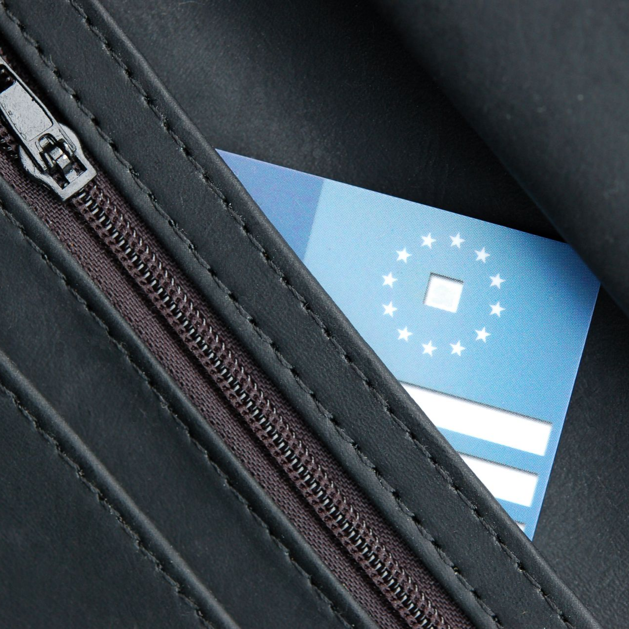Gros plan sur un portefeuille noir laissant apparaître partiellement une carte européenne d'assurance maladie.
