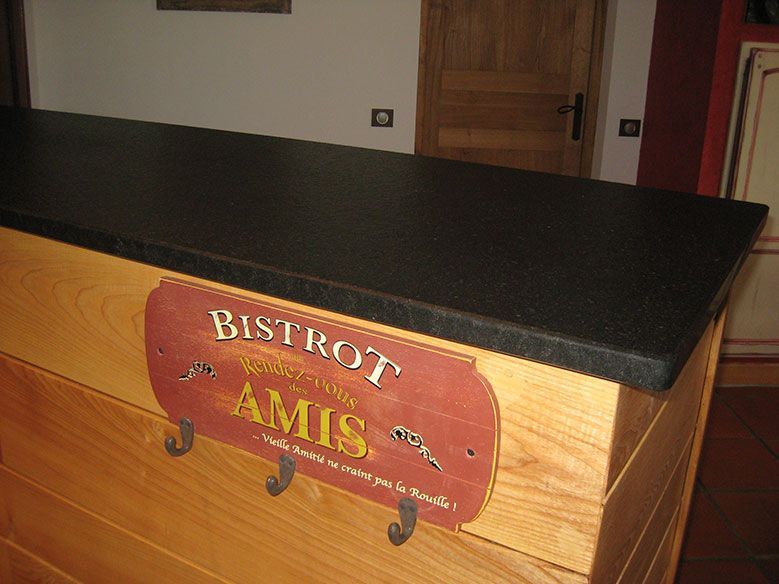 Bar en bois avec comptoir noir et enseigne Bistrot Amis, porte et mur marron en arrière-plan.