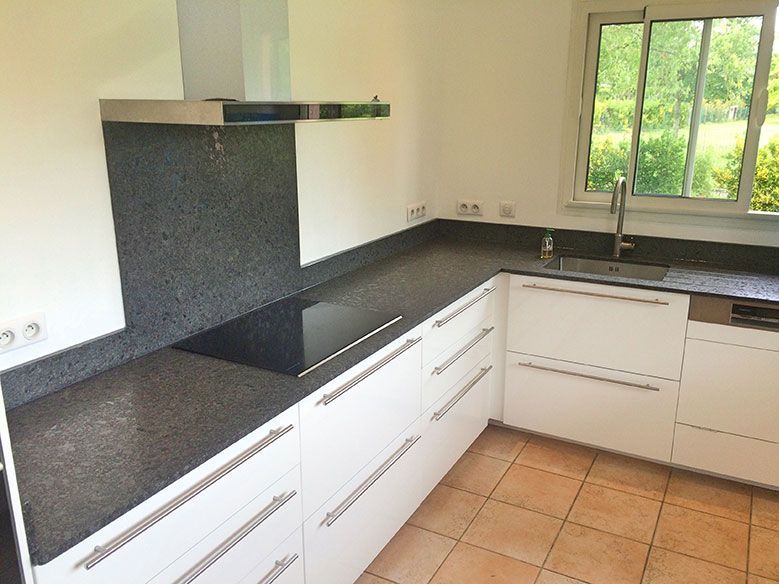 Cuisine moderne avec armoires blanches, comptoirs foncés et électroménagers en acier inoxydable.